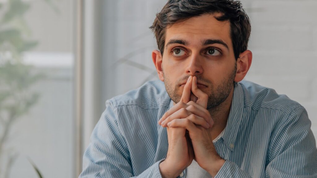 Zamyślony mężczyzna myśli nad raportem który musi przygotować do pracy.