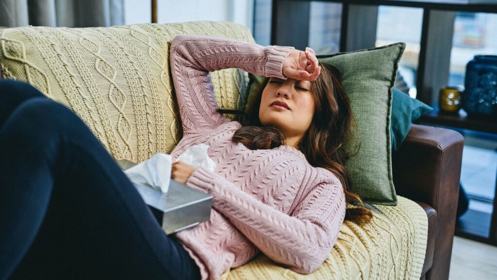 Chora kobieta ma katar i gorączkę, ponieważ zaraziła się grypą od kolegi z pracy.