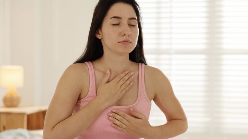 Kobieta wczesnym rankiem próbuje uspokoić oddech z dłonią ułożoną powyżej klatki piersiowej.