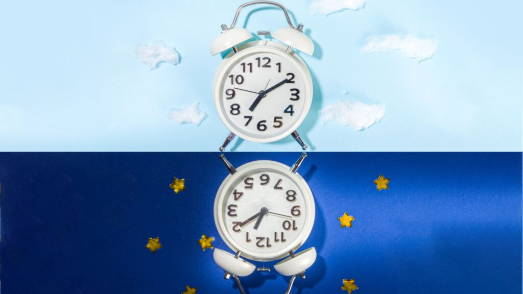 Lustrzane odbicie wskazówek zegara z ciemniejszym niebieskim tłem otoczonym gwiazdkami.