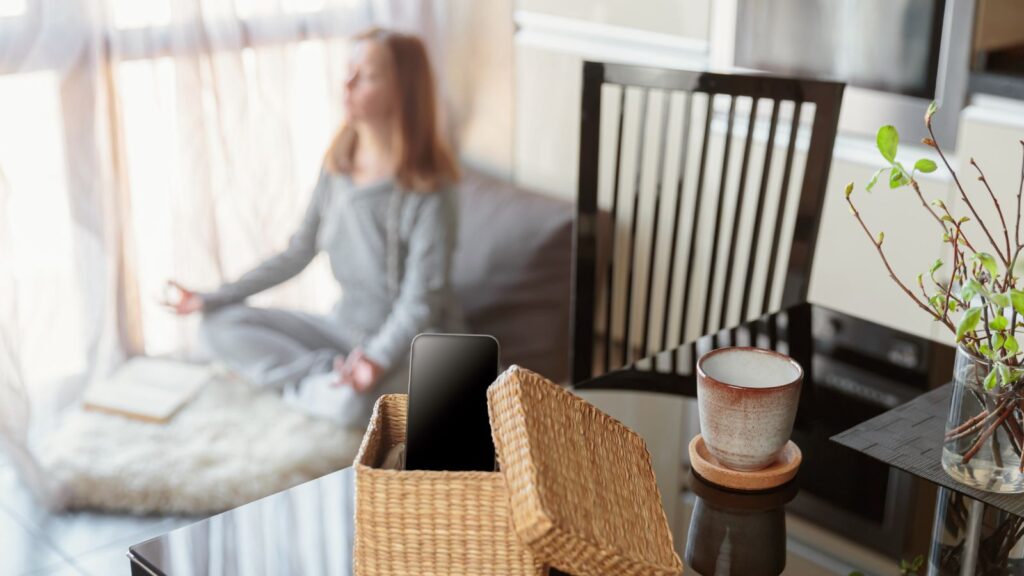 Kobieta siedzi na łóżku i medytuje chcąc spędzić weekend offline bez telfeonu.