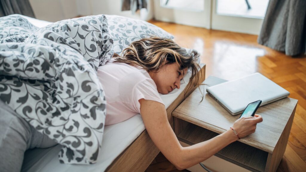 Kobieta w łóżku rano, starająca się zmotywować do wstania.